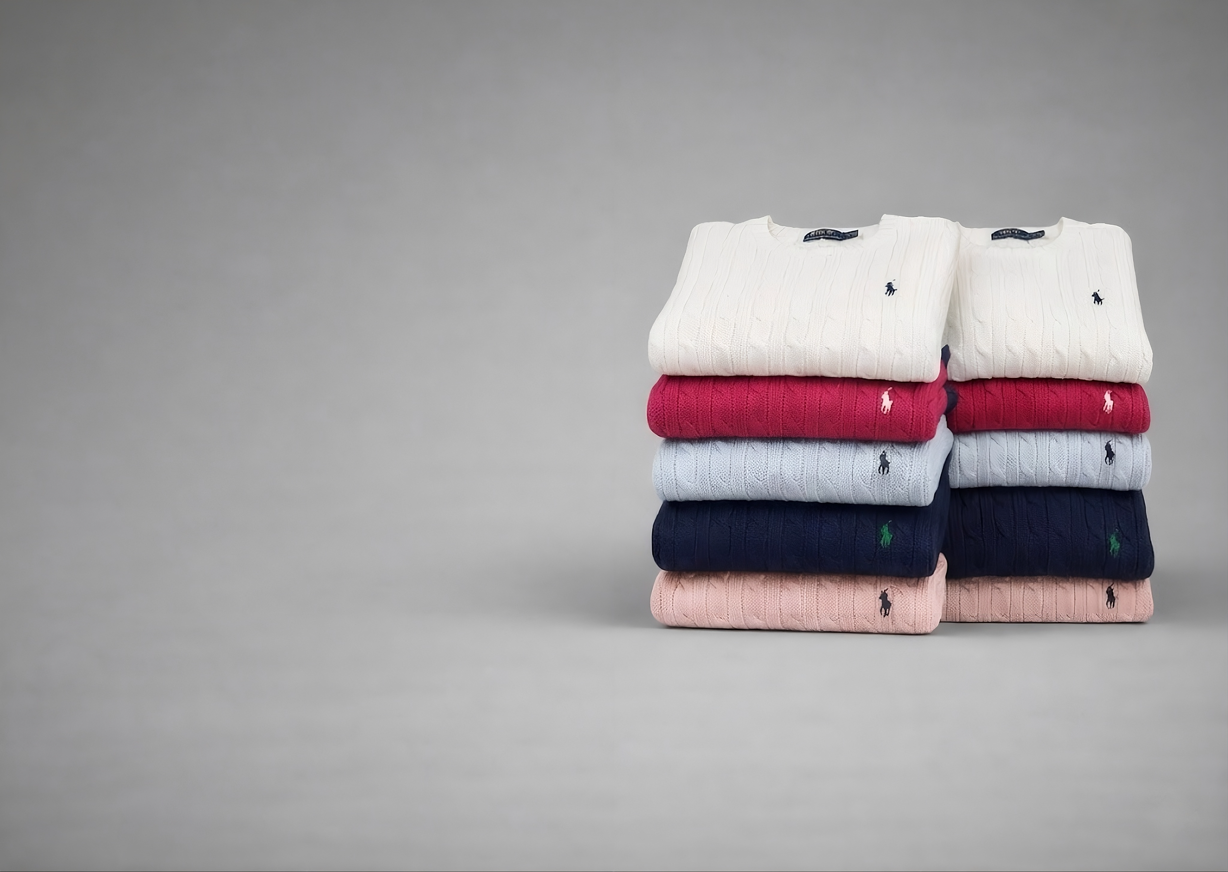 Bundle of ralph lauren jumpers stacked on grey background